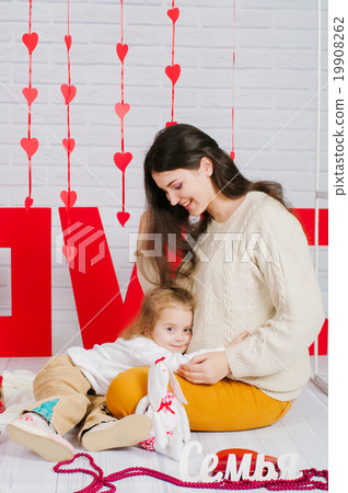 Young mother with her baby daughter with red decor Young mother with her baby daughter with red decor 19908262