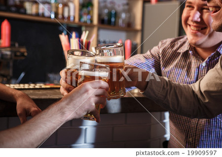 Happy friends drinking beer at counter in pub Happy friends drinking beer at counter in pub 19909597