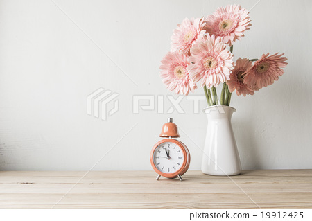 Stock Photo: flowers and alarm clock on a white wall shelf