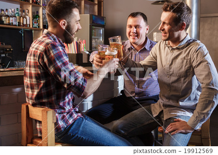 Happy friends drinking beer at counter in pub Happy friends drinking beer at counter in pub 19912569