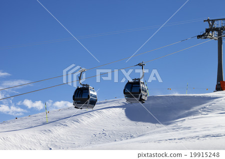 Gondola lift on ski resort at windy sun day 19915248
