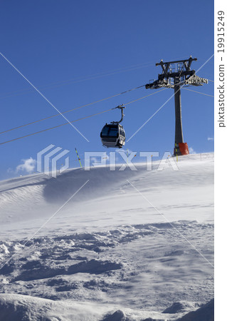 Gondola lift on ski resort at windy sun day 19915249