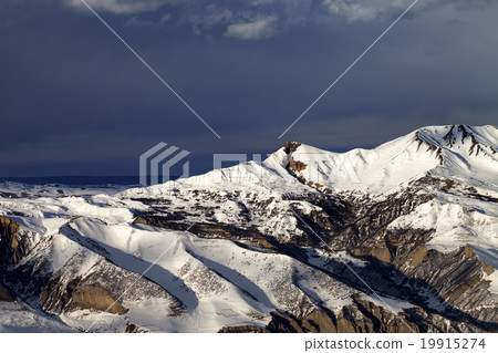 Winter mountains at sun evening and dark clouds 19915274