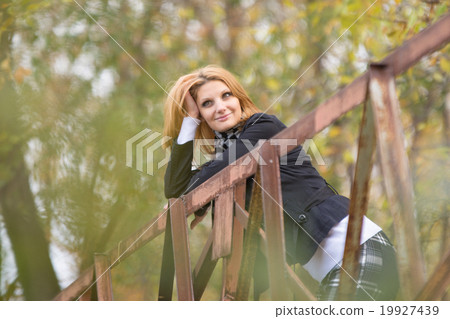 Young beautiful girl standing bridge, leaning on the railing and looking pensively into the distance 19927439