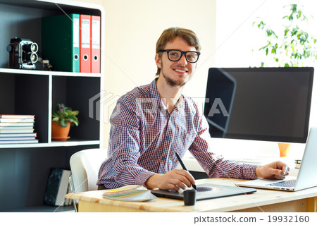 Young artist drawing something on graphic tablet at the home off 19932160