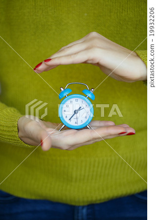 Little blue alarm clock in the hands of woman Little blue alarm clock in the hands of woman 19932206