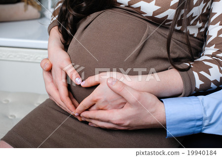husband is tenderly hugging his pregnant wife  19940184