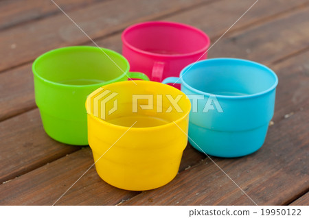 Colored cups on the wooden background 19950122