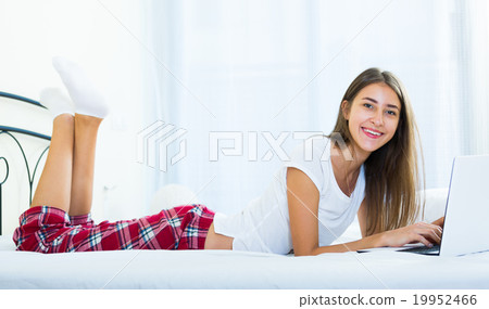 Cheerful student girl studing with laptop in bed Cheerful student girl studing with laptop in bed 19952466