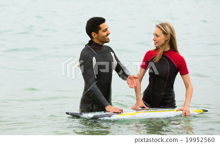 Couple in wetsuits with surf boards 19952560