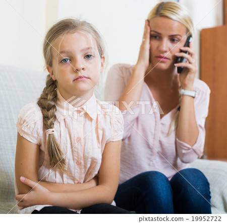 Worried mother calling doctor for daughter with abdominal pains Worried mother calling doctor for daughter with abdominal pains 19952722