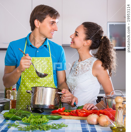 Couple at kitchen with vegetables at the table. Couple at kitchen with vegetables at the table. 19953114