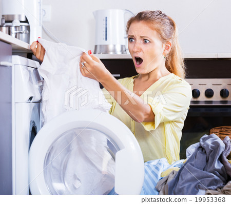 Upset girl looking at linen after laundry Upset girl looking at linen after laundry 19953368