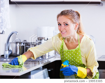 Woman dusting kitchen top at home Woman dusting kitchen top at home 19953385