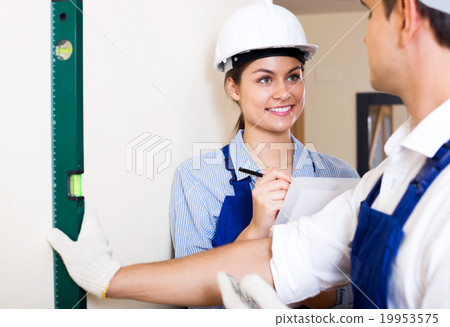 Constructor showing assistant measuring the wall Constructor showing assistant measuring the wall 19953575