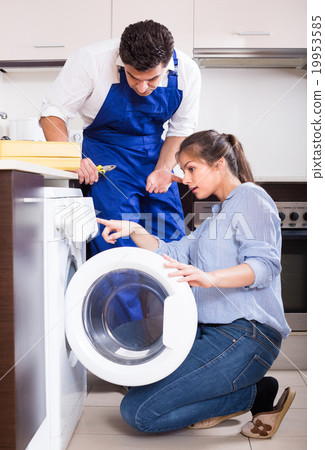Repairman and woman near washing machine. 19953585