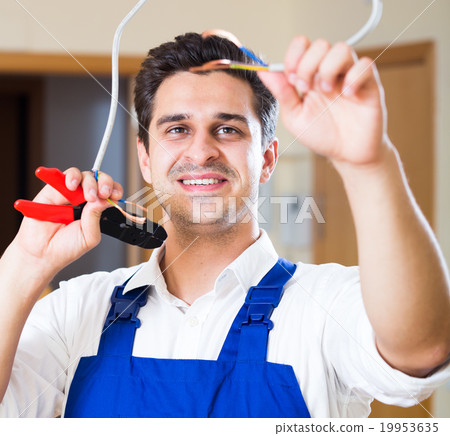Repairman cutting wires with pliers in domestic interior Repairman cutting wires with pliers in domestic interior 19953635