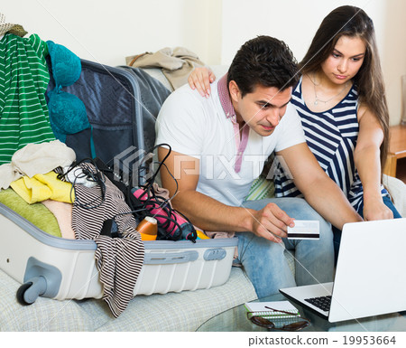 adults sitting near laptop and luggage adults sitting near laptop and luggage 19953664