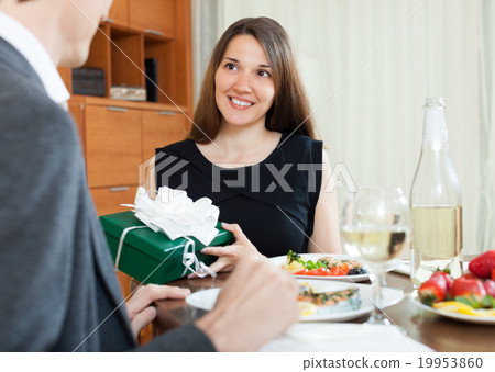 Girl giving gift during romantic dinner Girl giving gift during romantic dinner 19953860