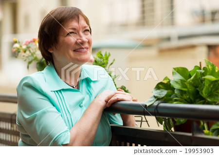 Cheerful senior woman sitting on terrace 19953903