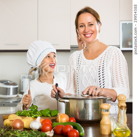图库照片: smiling girl and mom at kitchen