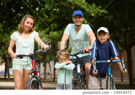 cheerful family of four with bicycles walking 19954471