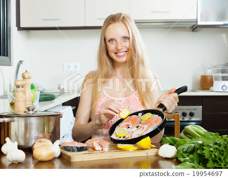 Smiling woman cooking salmon fish with lemon Smiling woman cooking salmon fish with lemon 19954697