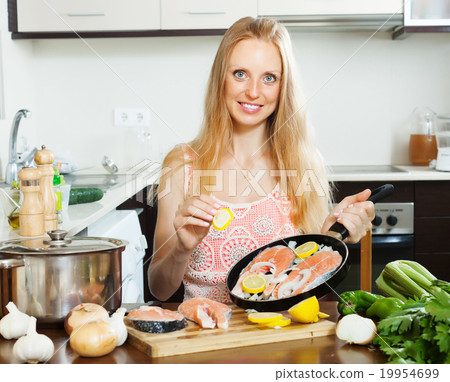 woman cooking salmon with lemon on pan woman cooking salmon with lemon on pan 19954699