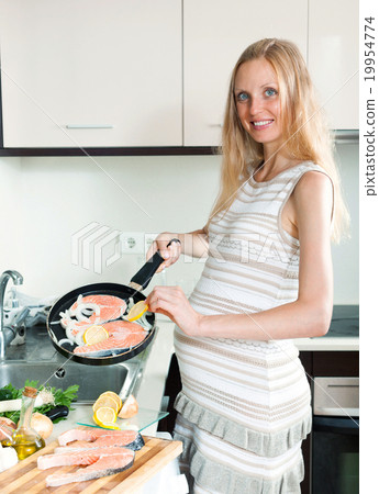 Pregnant housewife cooking salmon Pregnant housewife cooking salmon 19954774