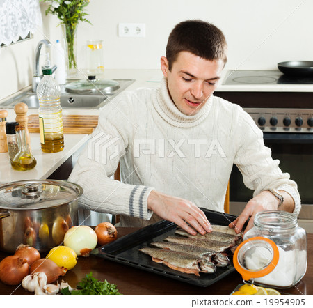 guy cooking raw fish in roasting pan 19954905