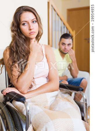 Sad man with girlfriend in invalid chair 19954955