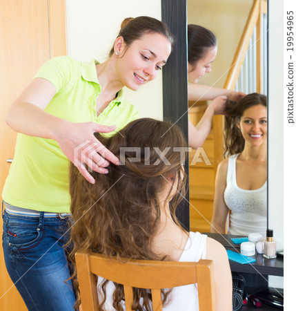 Girl brushing her friend at home 19954965