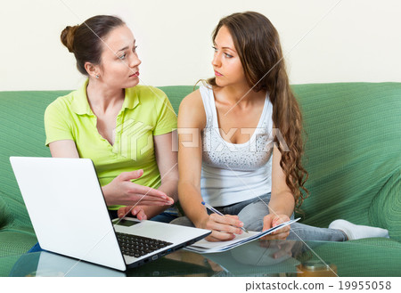 Serious girl looking documents with laptop Serious girl looking documents with laptop 19955058