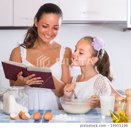 Happy girl helping mother at kitchen. Happy girl helping mother at kitchen. 19955196
