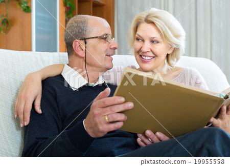 Senior spouses with picture album indoor 19955558