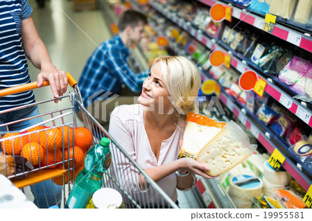 Young spouses buying cheddar in cheese section 19955581