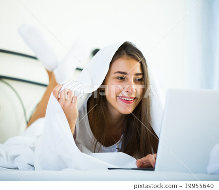 Teenage girl chatting online covered with blanket Teenage girl chatting online covered with blanket 19955640