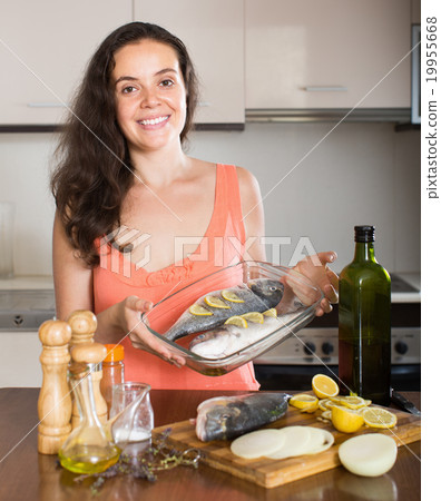 Happy housewife cooking fish in frying pan 19955668