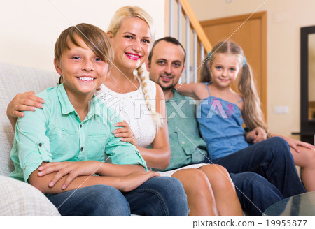 parents with two children posing in home interior 19955877