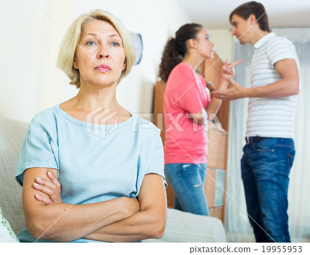 Mature woman watching young family couple quarrel at home 19955953