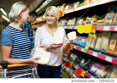 Adult girl with senior mother in cheese section of supermarket Adult girl with senior mother in cheese section of supermarket 19956020
