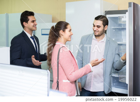 couple choosing new refrigerator in hypermarket couple choosing new refrigerator in hypermarket 19956022