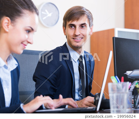 Two young managers using laptop at work Two young managers using laptop at work 19956024