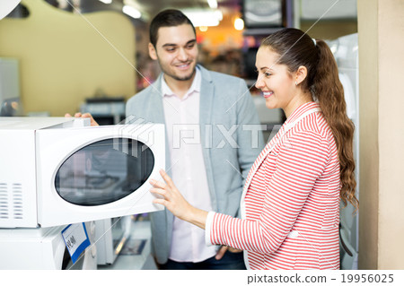 Happy family couple choosing new microwave Happy family couple choosing new microwave 19956025