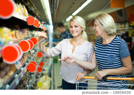 Customers choosing sausages in shop. 19956030