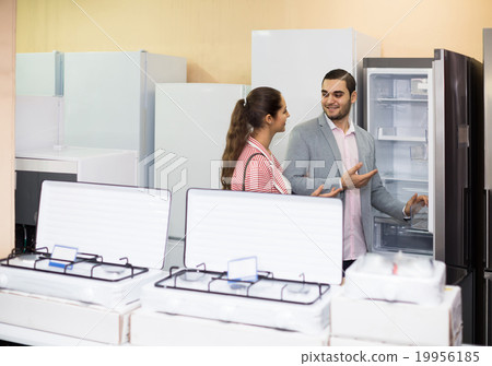 couple choosing new refrigerator in hypermarket couple choosing new refrigerator in hypermarket 19956185