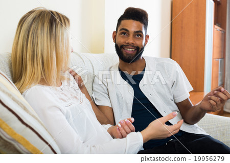 Happy young people sitting indoors and talking 19956279