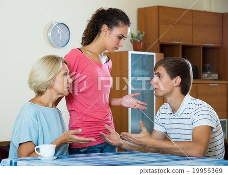 Angry wife and mother-in-law rebuking young man Angry wife and mother-in-law rebuking young man 19956369