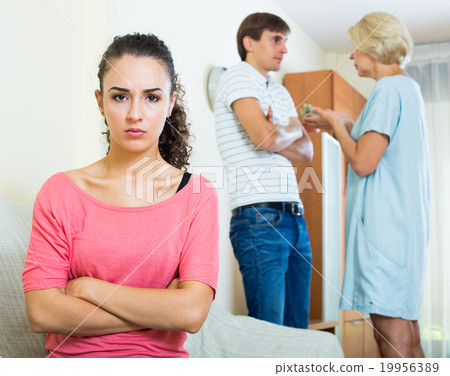 Upset girl watching her husband and senior mother fighting Upset girl watching her husband and senior mother fighting 19956389