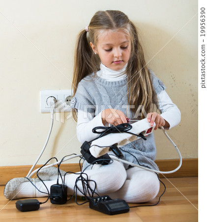 Small girl playing with charging units and smiling 19956390